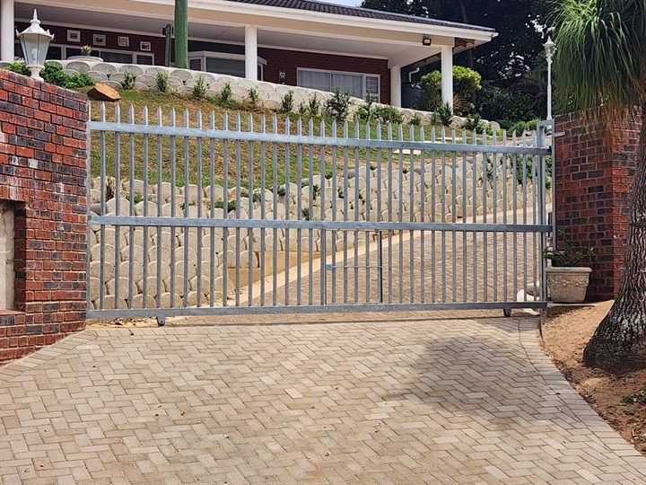Galvanised steel sliding driveway gate fitted between brick pillars