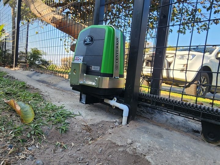 Green gate motor and steel rack fitted to a black mesh sliding gate